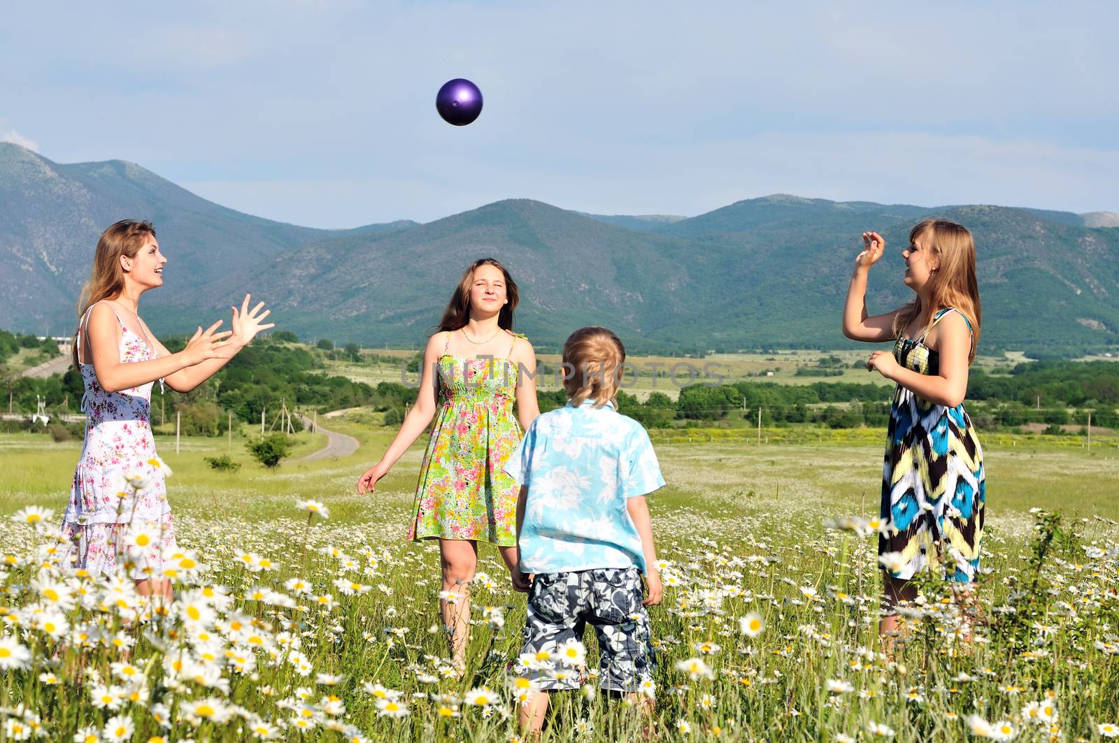 boy and teen girls playing a ball in field 