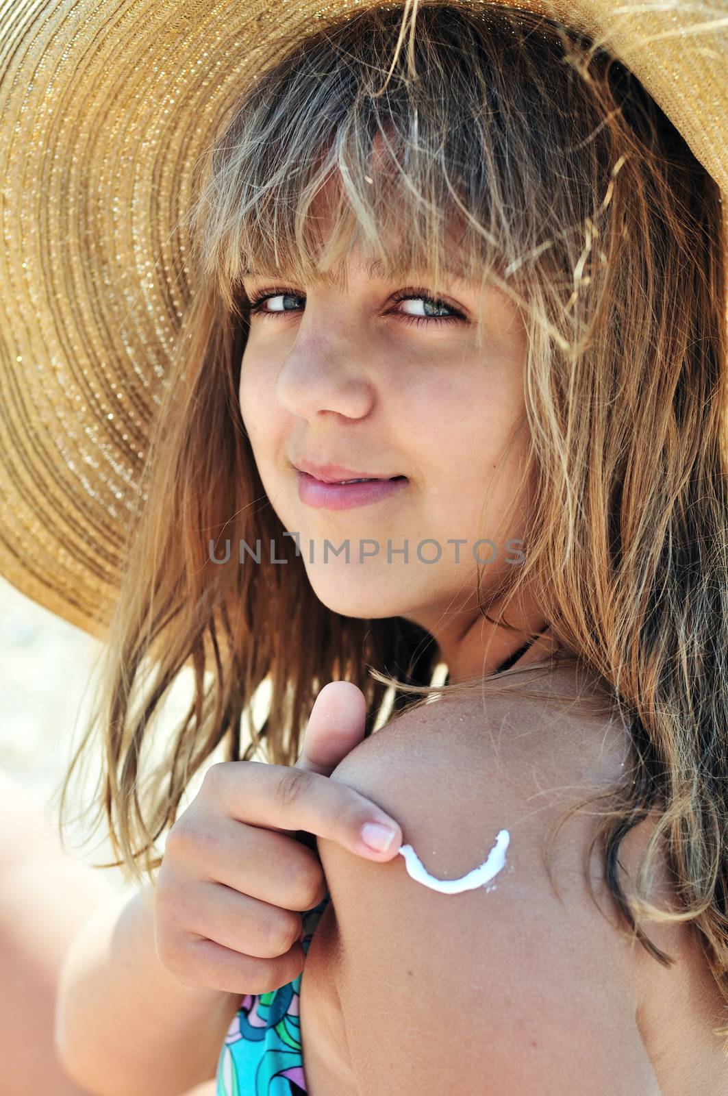 teenager girl wearing straw hat using sunscreen 