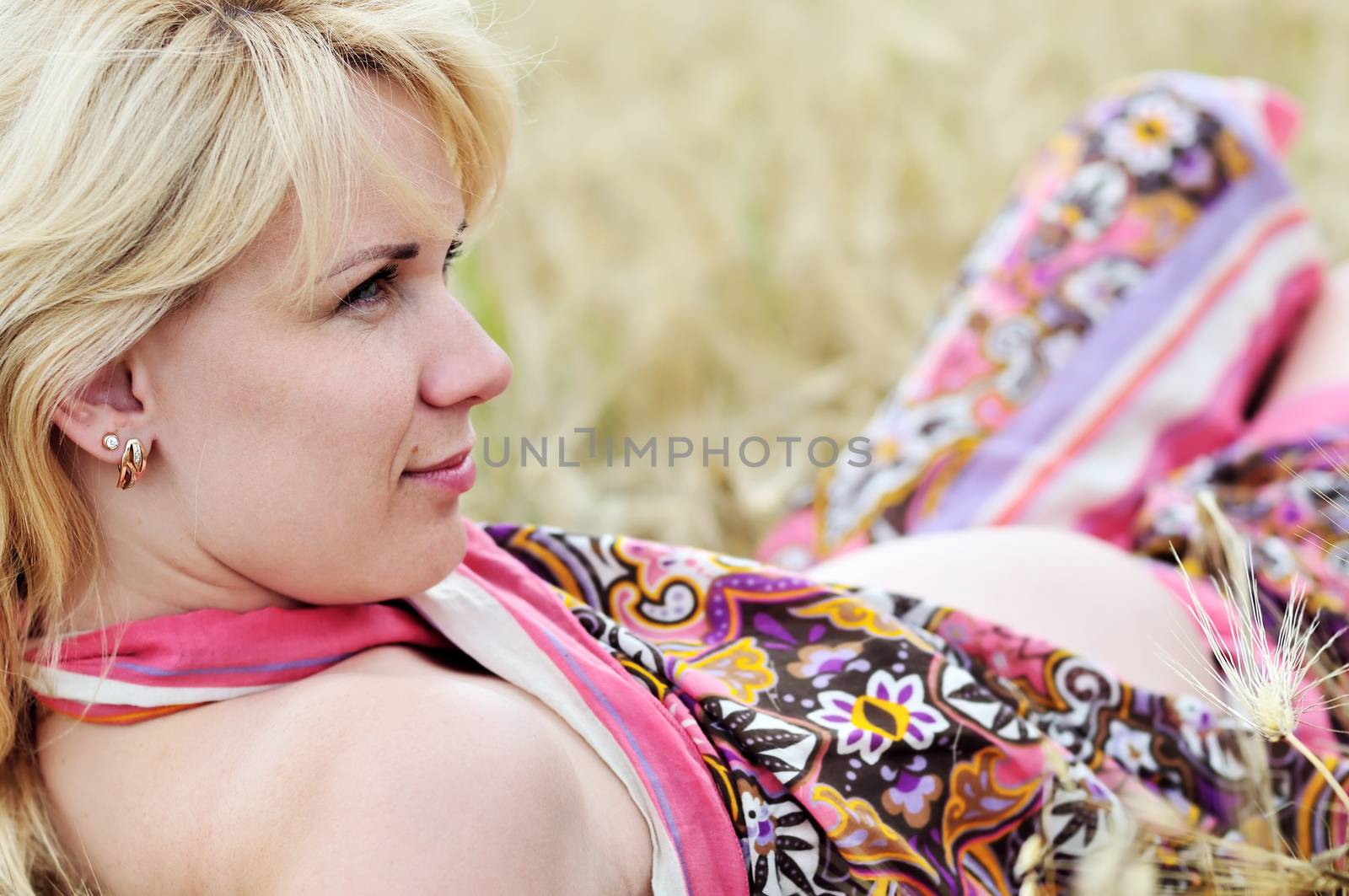blonde pregnant woman relaxing in the wheat field