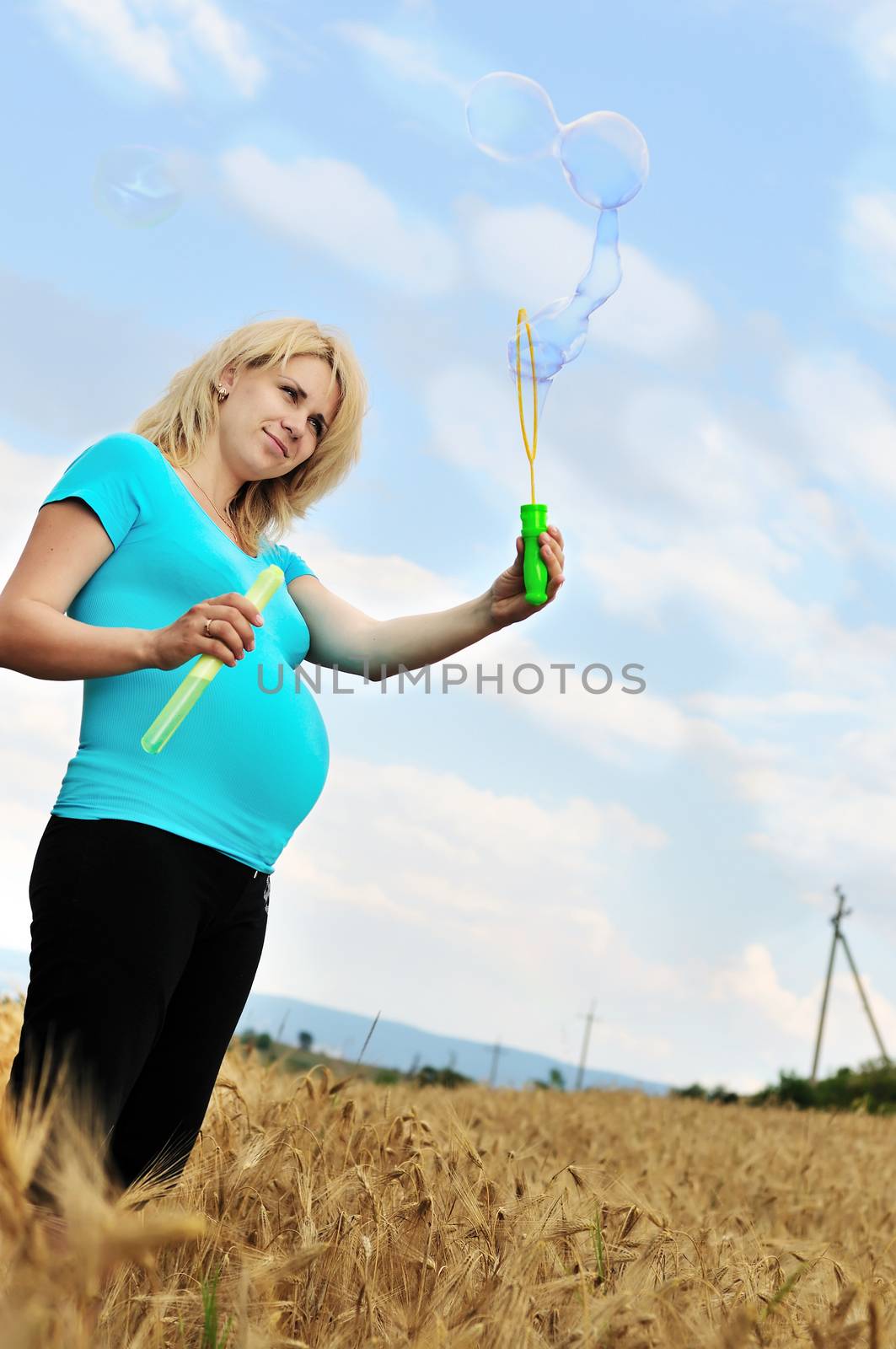 pregnant woman with soap bubbles in the wheat field