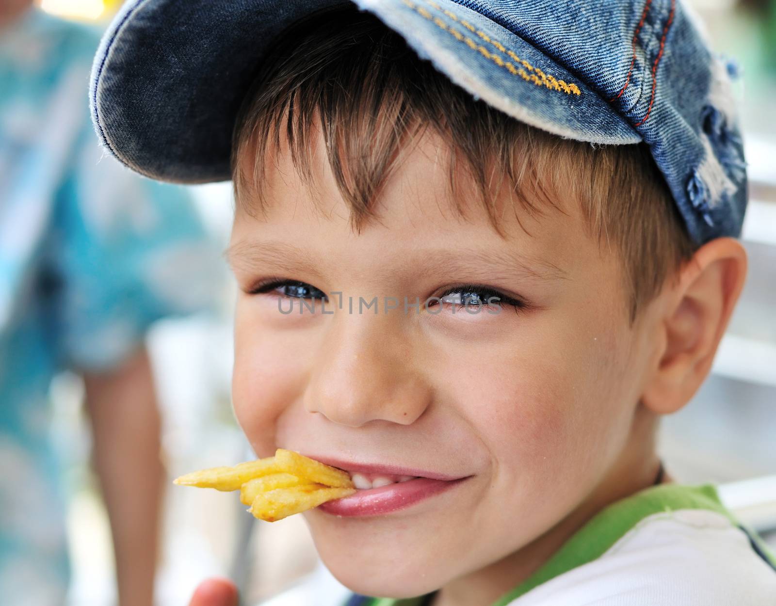 little boy eating french fries in cafe 