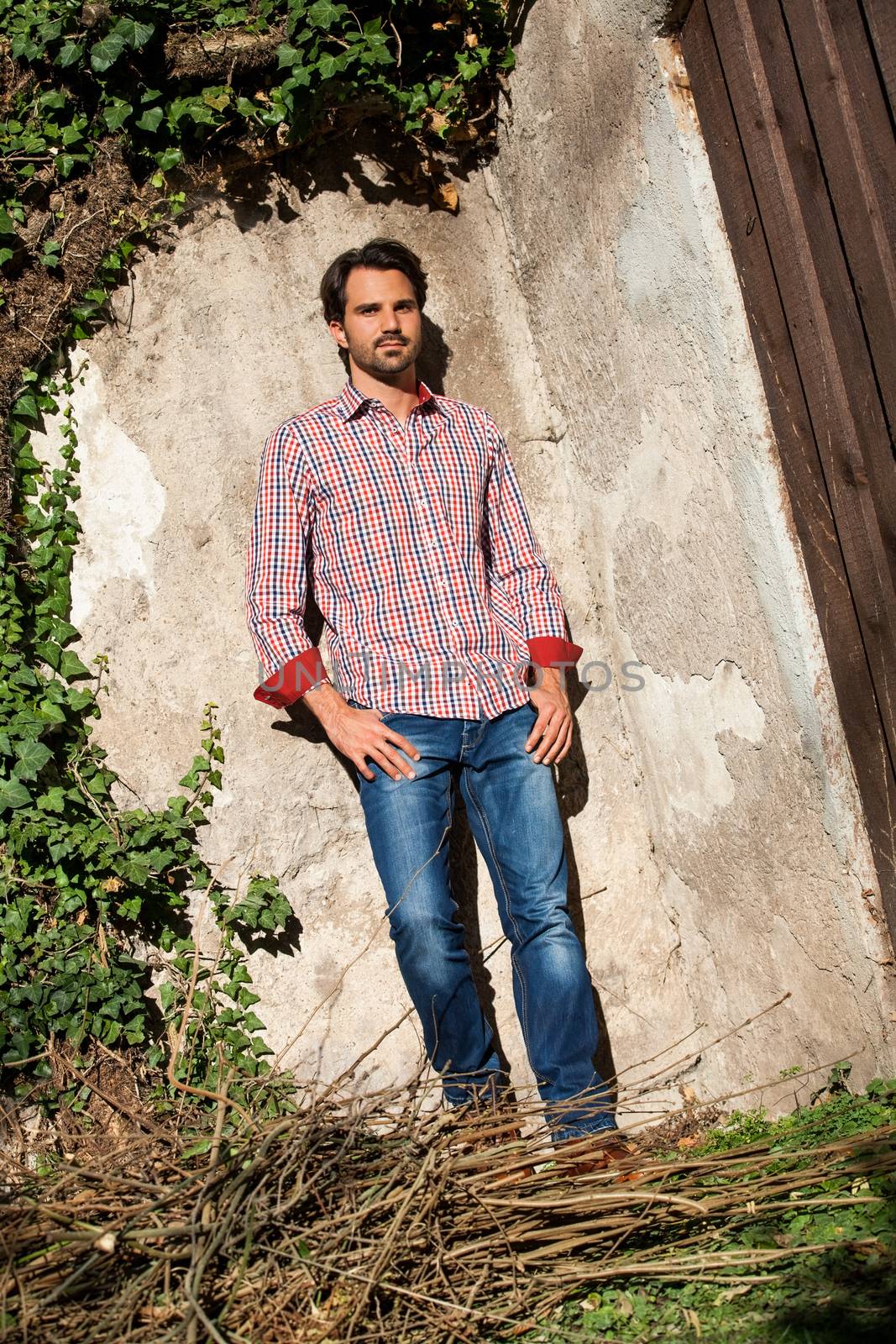 Smiling male model sitting on wooden crate with legs crossed