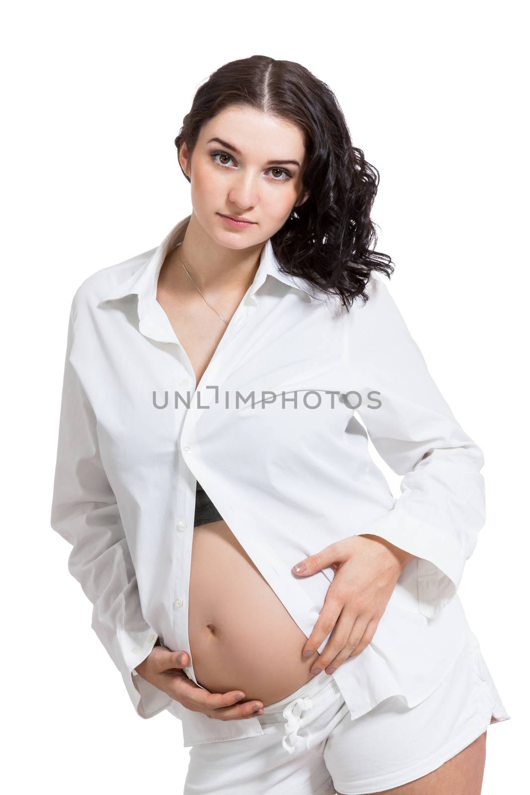 Beautiful young pregnant expectant mother bonding with her unborn child cradling her swollen abdomen with her hand with a look of love and tenderness, isolated on white