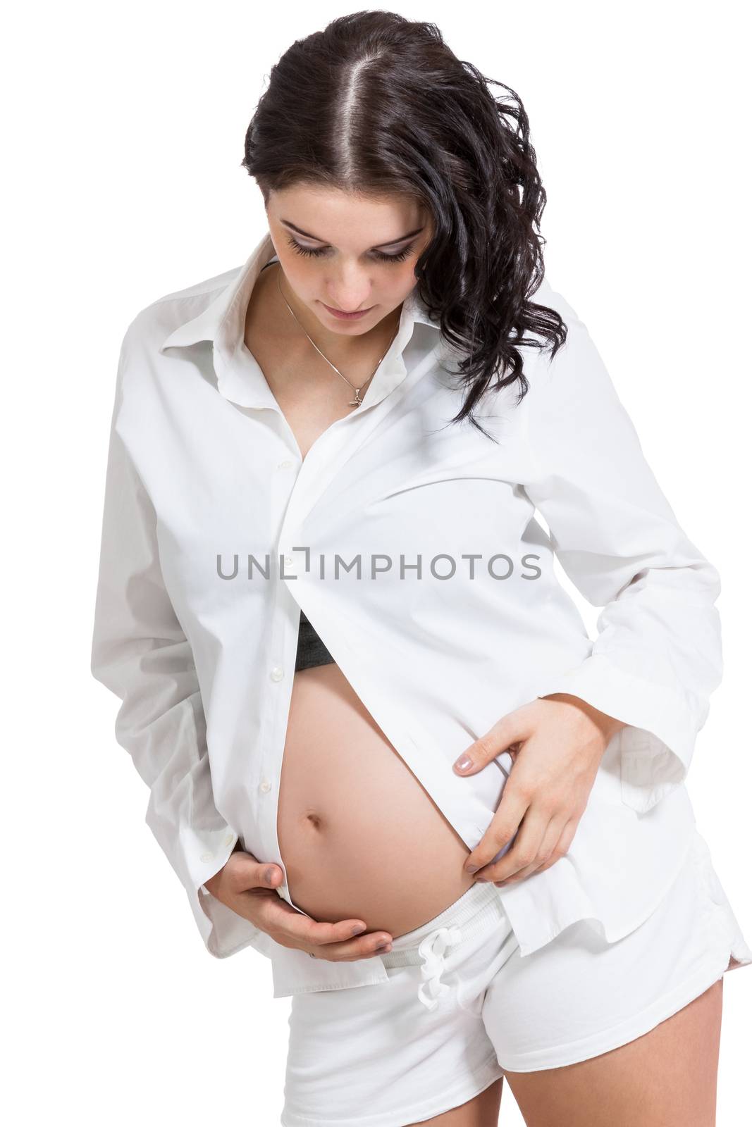 Beautiful young pregnant expectant mother bonding with her unborn child cradling her swollen abdomen with her hand with a look of love and tenderness, isolated on white