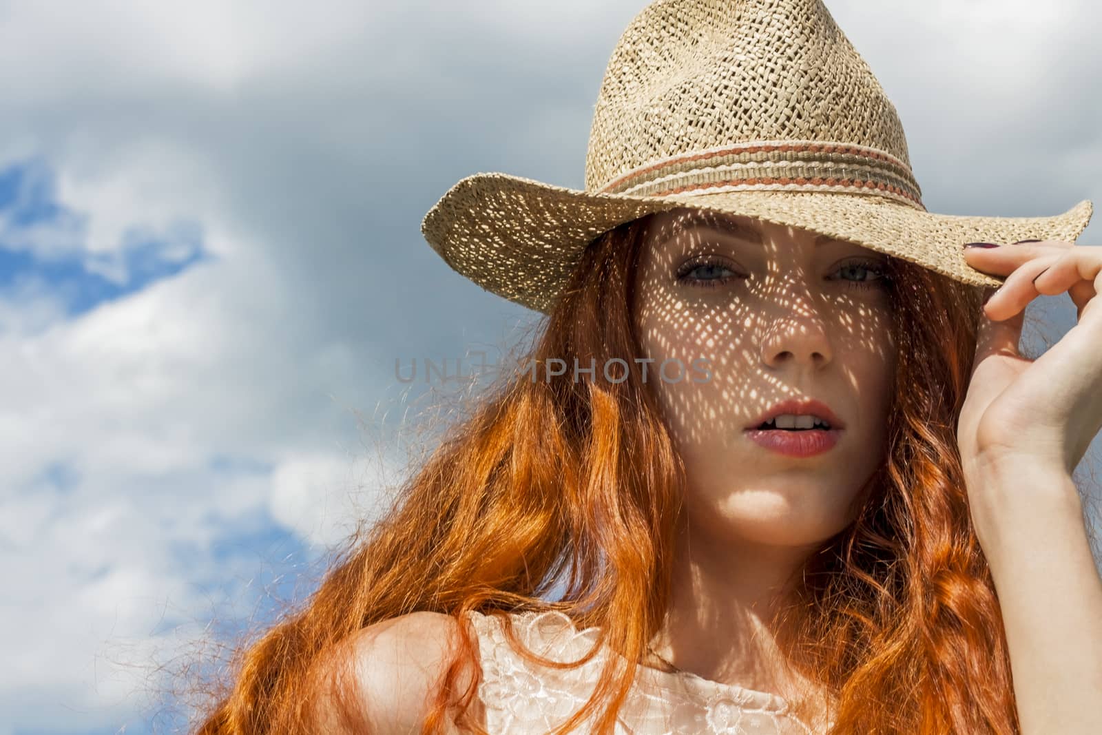Close up Gorgeous Blond Woman Wearing Hat, Looking at Camera, on Cloudy Sky background