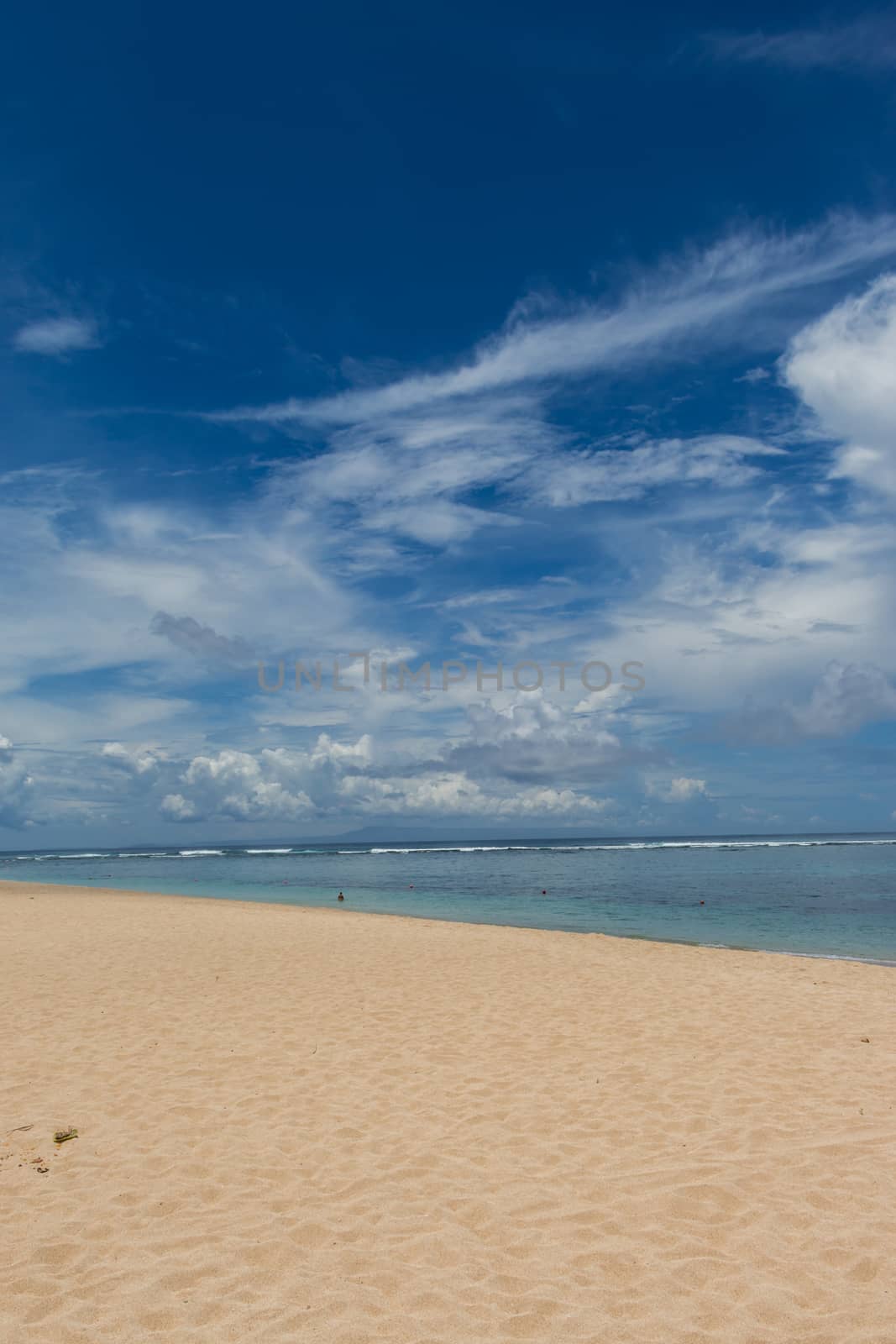 Beautiful tropical beach with lush vegetation fringing golden sand and a tranquil ocean with gentle surf breaking on the beach