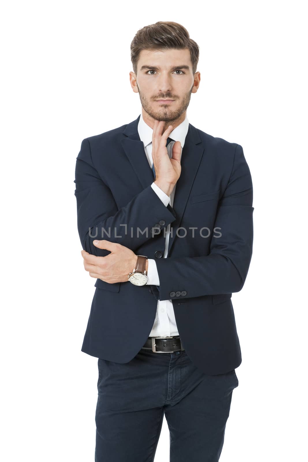 Stylish successful handsome young businessman standing in a relaxed pose with his hands in his pockets and his suit jacket open, isolated on white