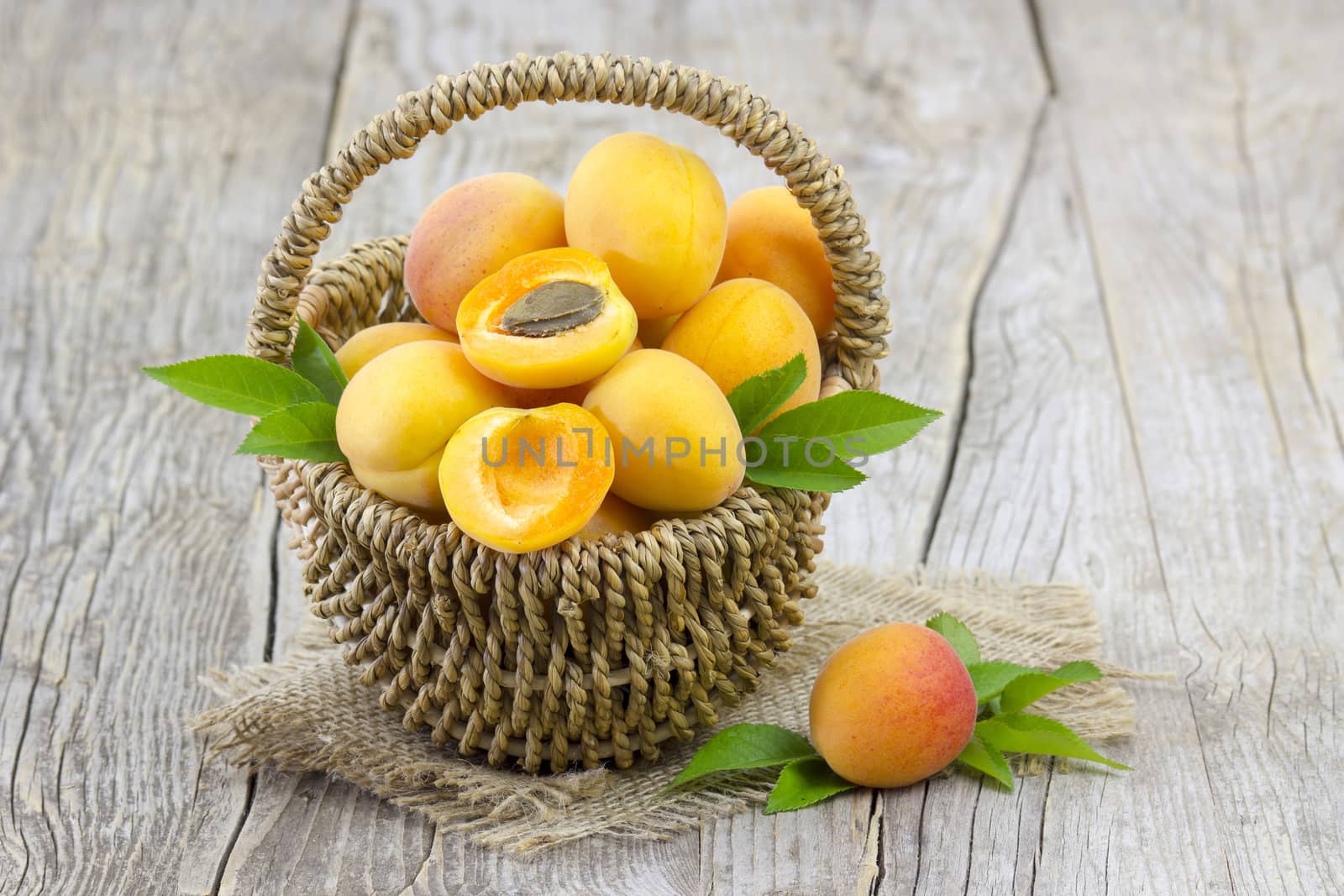 fresh apricots in a basket on wooden background by miradrozdowski