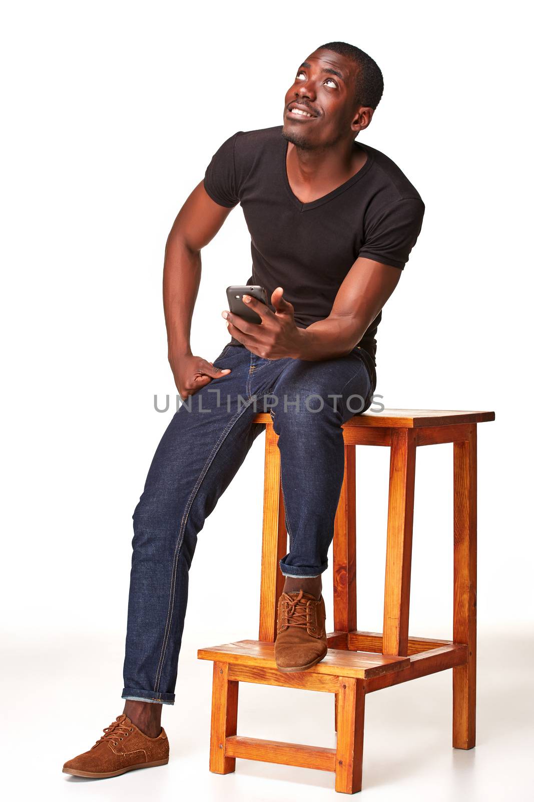 Portrait of smiling african man sitting on the chair and  talking on the phone, isolated on a white background