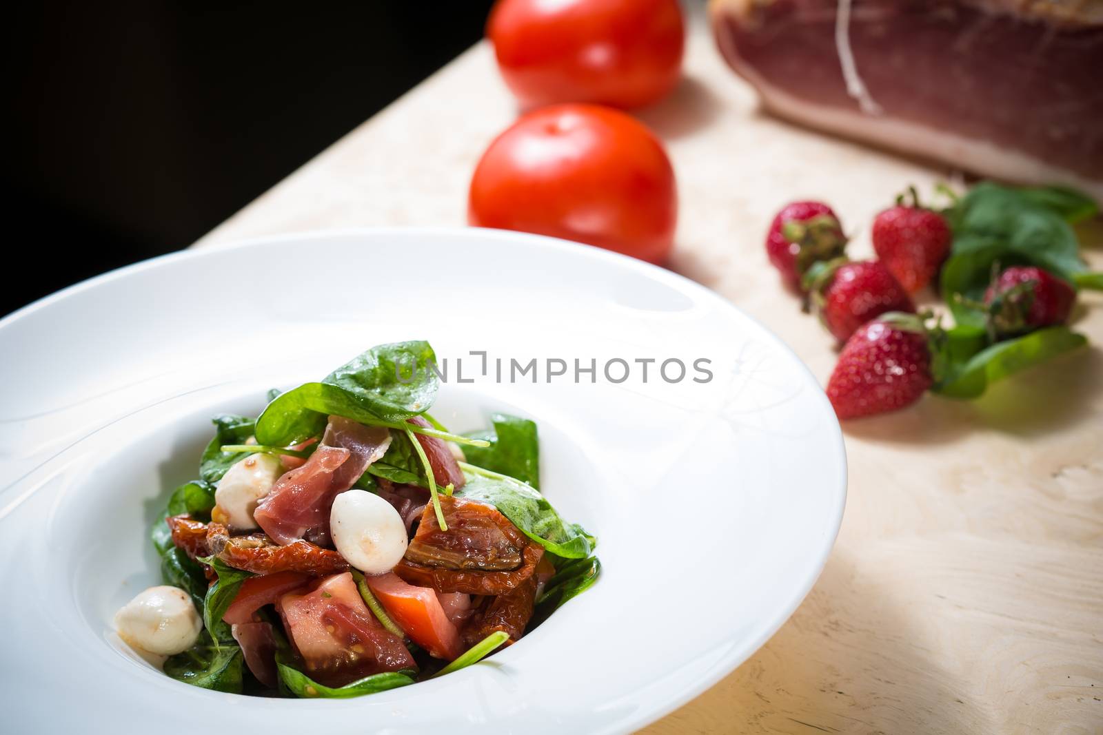 Salad with strawberry, prosciutto, herbs, cottage cheese and blackberry balsamic vinegar. Shallow dof.