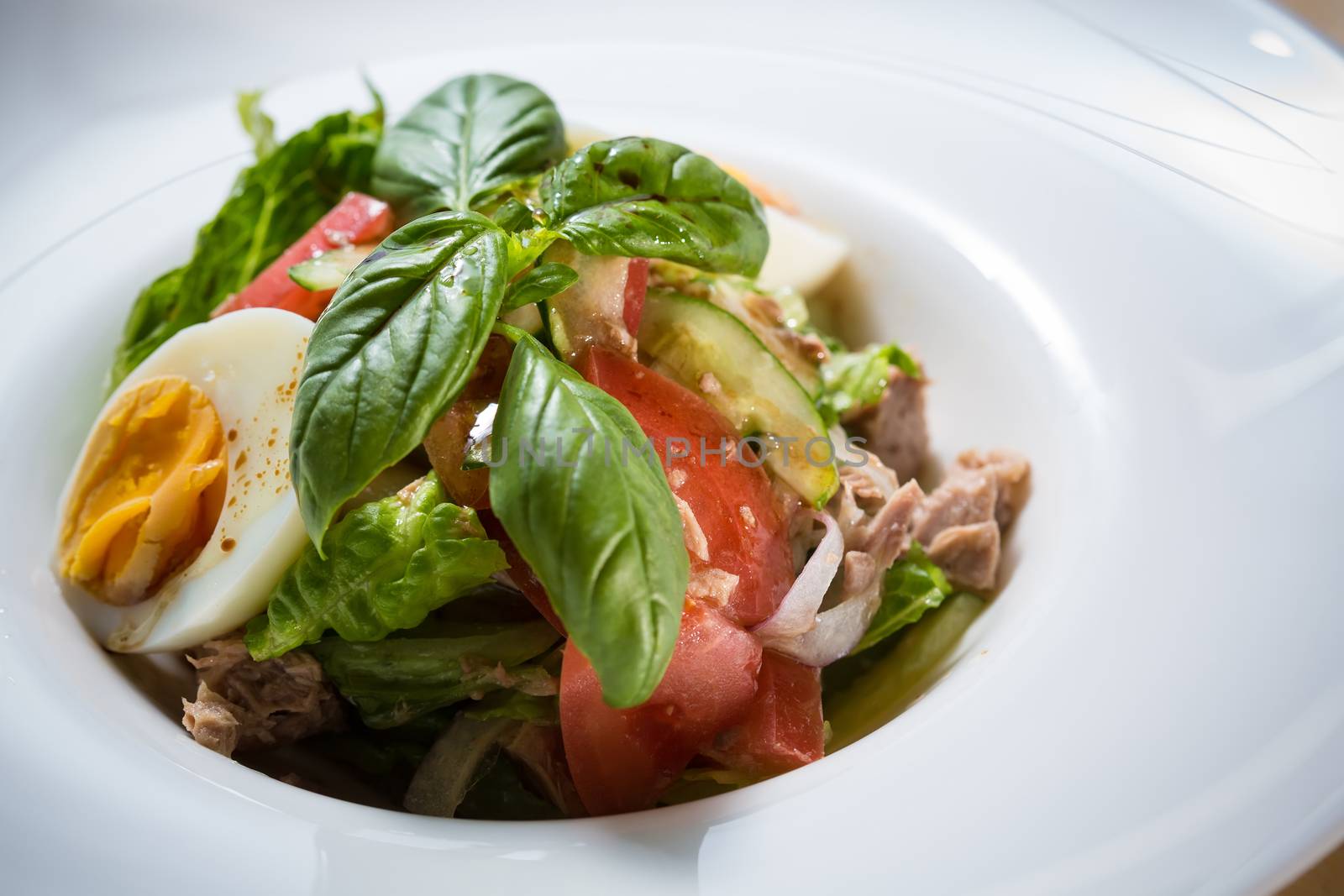 Closeup of plate of spring mix salad with strawberry, eggs and tuna