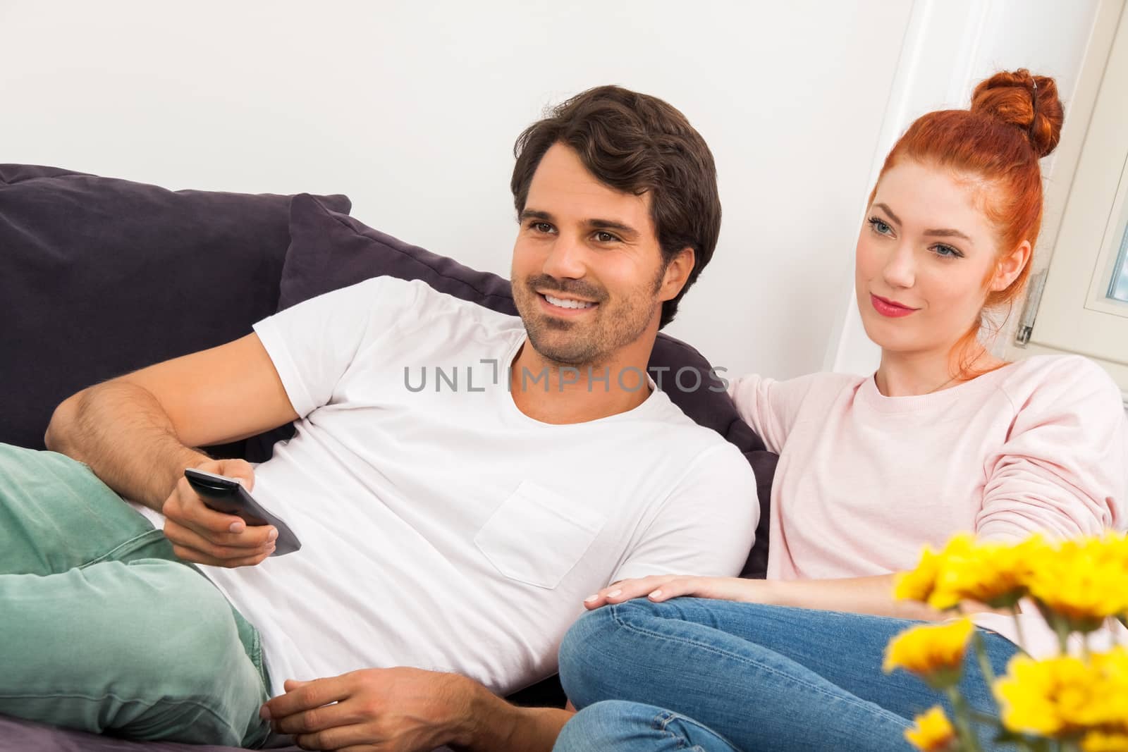 Close up Happy Young Couple Sitting on the Couch at the Living Room While Looking Something Into Distance.