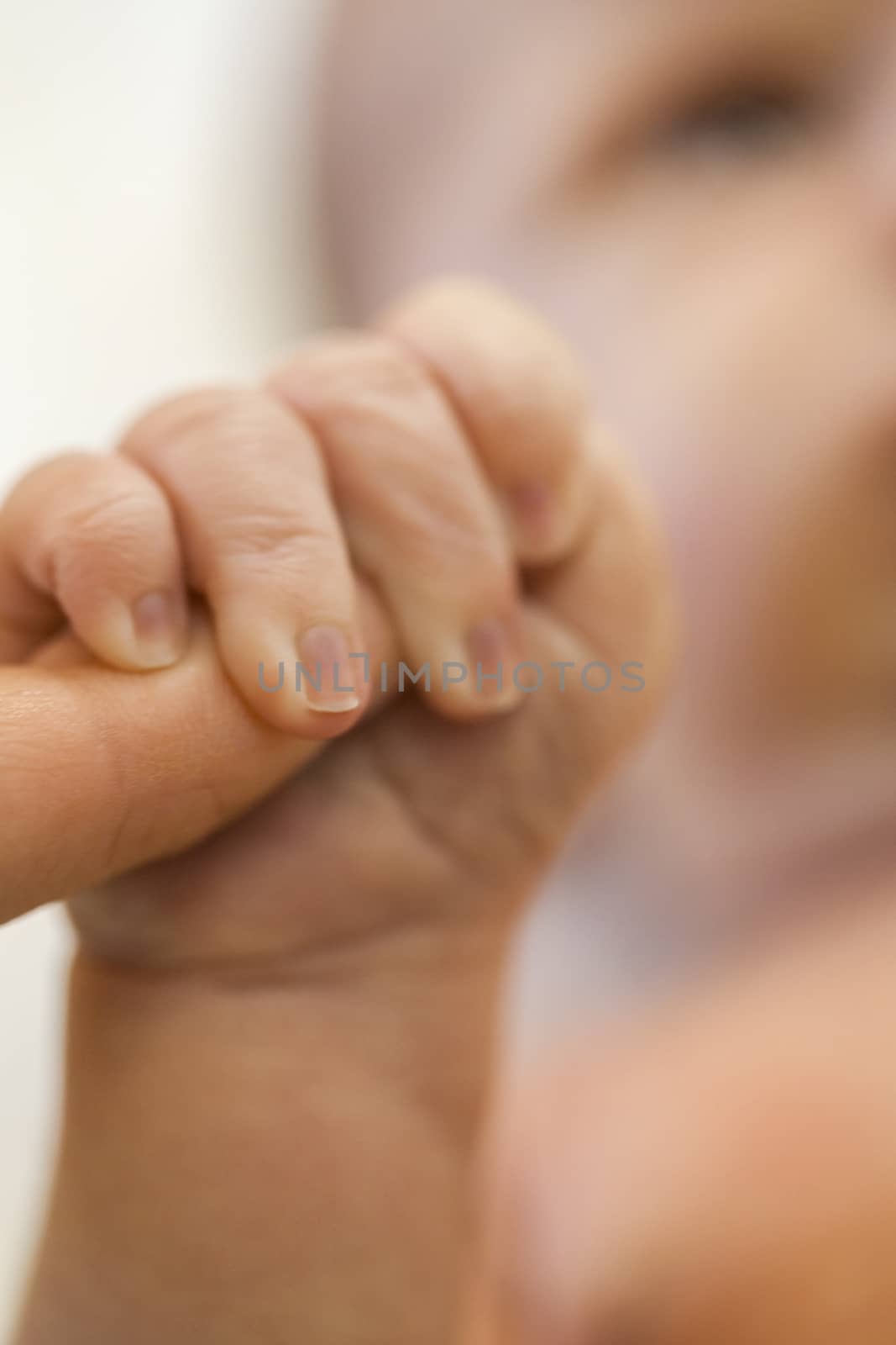 Tender love of a newborn infant with a closeup view of the hand of a tiny neonate clutching the finger of its parent in a show of trust, dependency and love