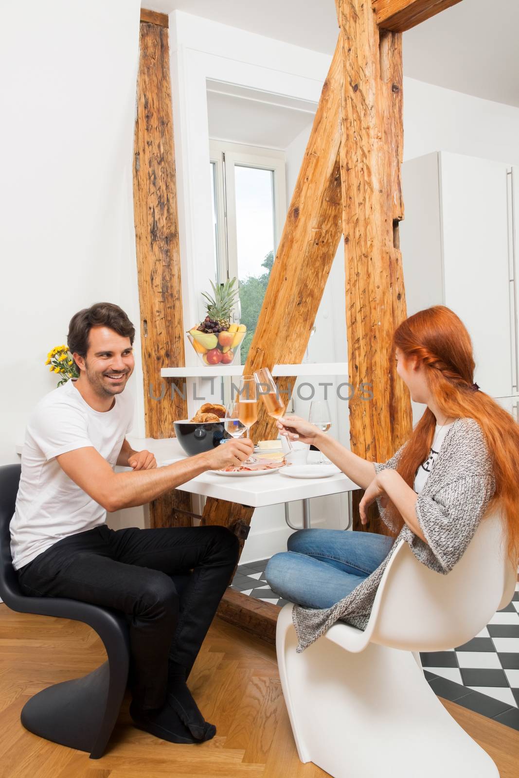 Young Couple Sitting at the Table and Slicing Freshly Baked Bread for their Ham Sandwich.