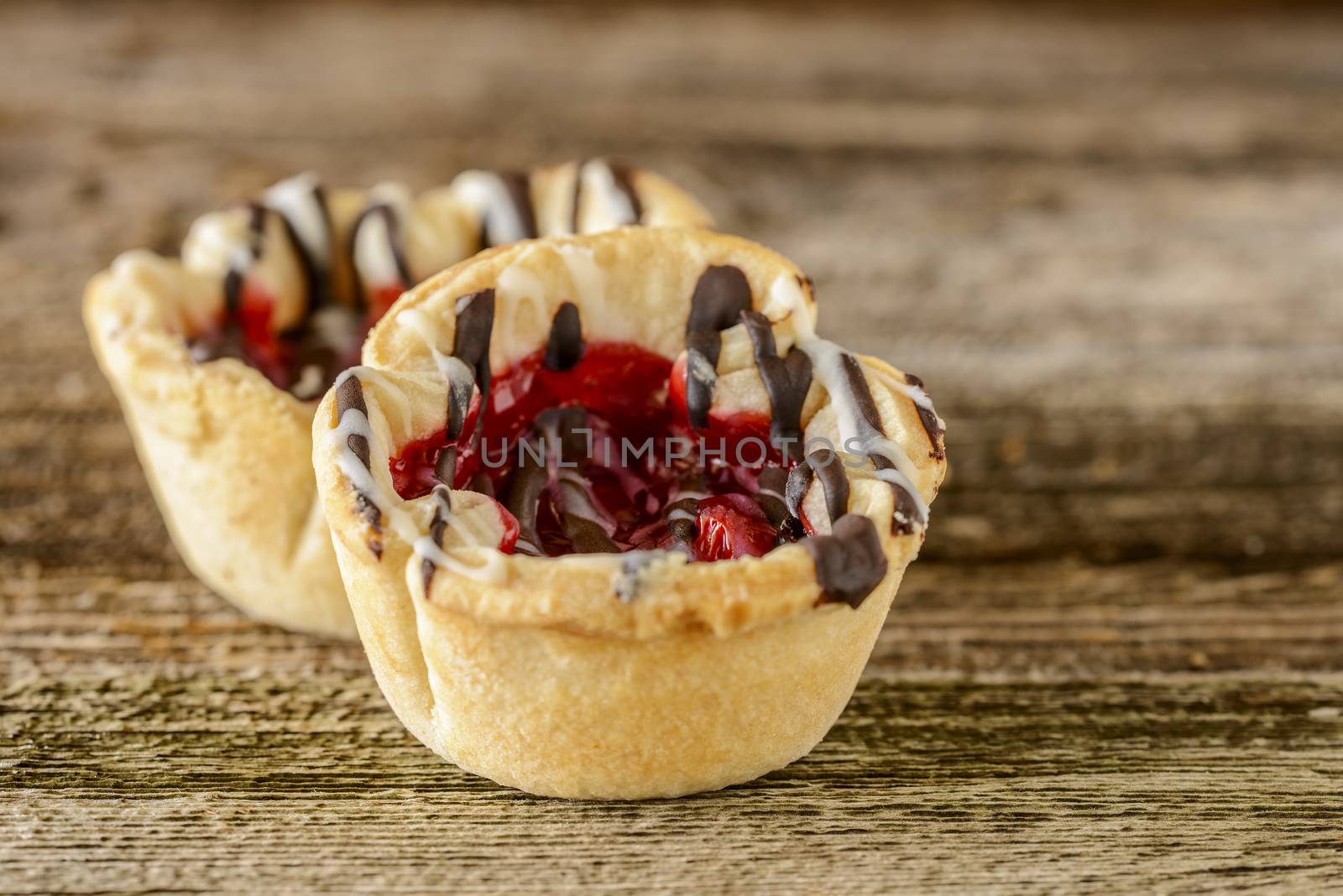 Homemade cherry tarts with chocolate and vanilla icing.