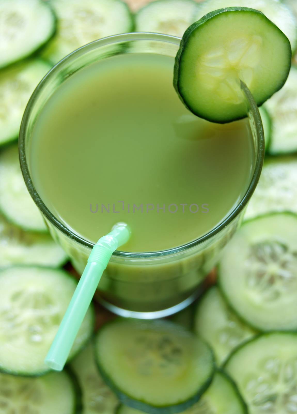 Fresh vegetable detox juice with cucumber slices in the background