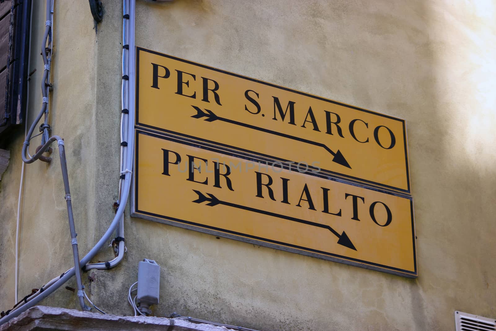 Directional sign to San Marco square and Rialto bridge on old Venetian building

