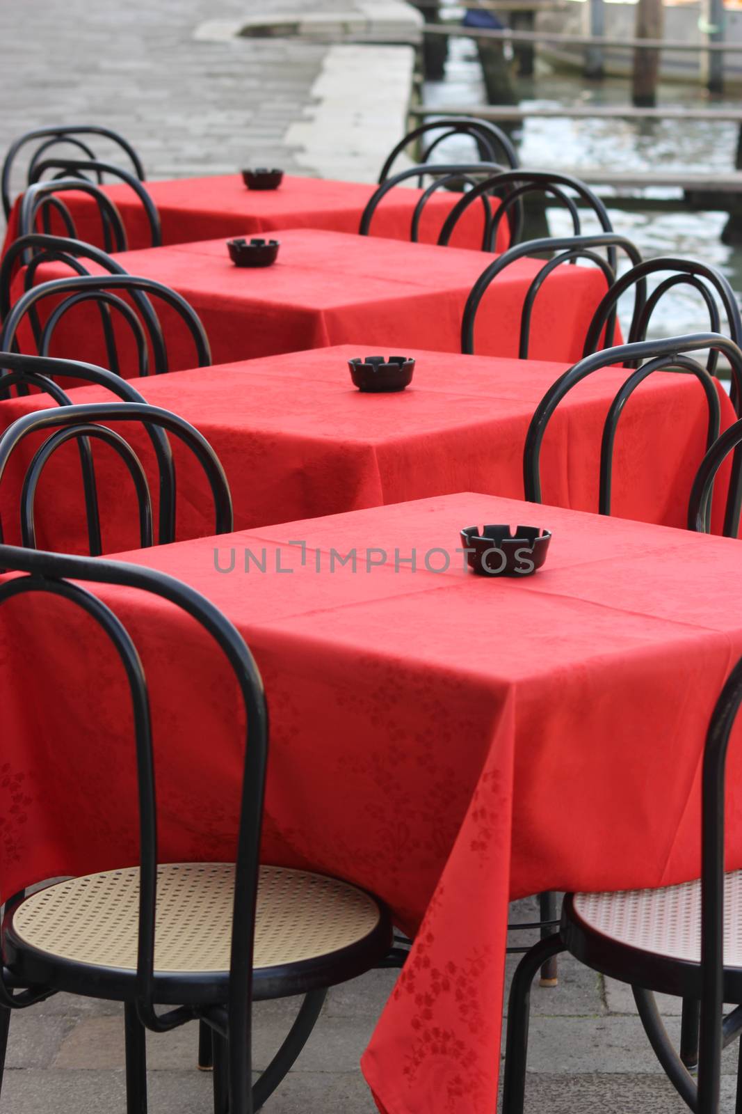 Red table and black chairs on a terrace in Venice