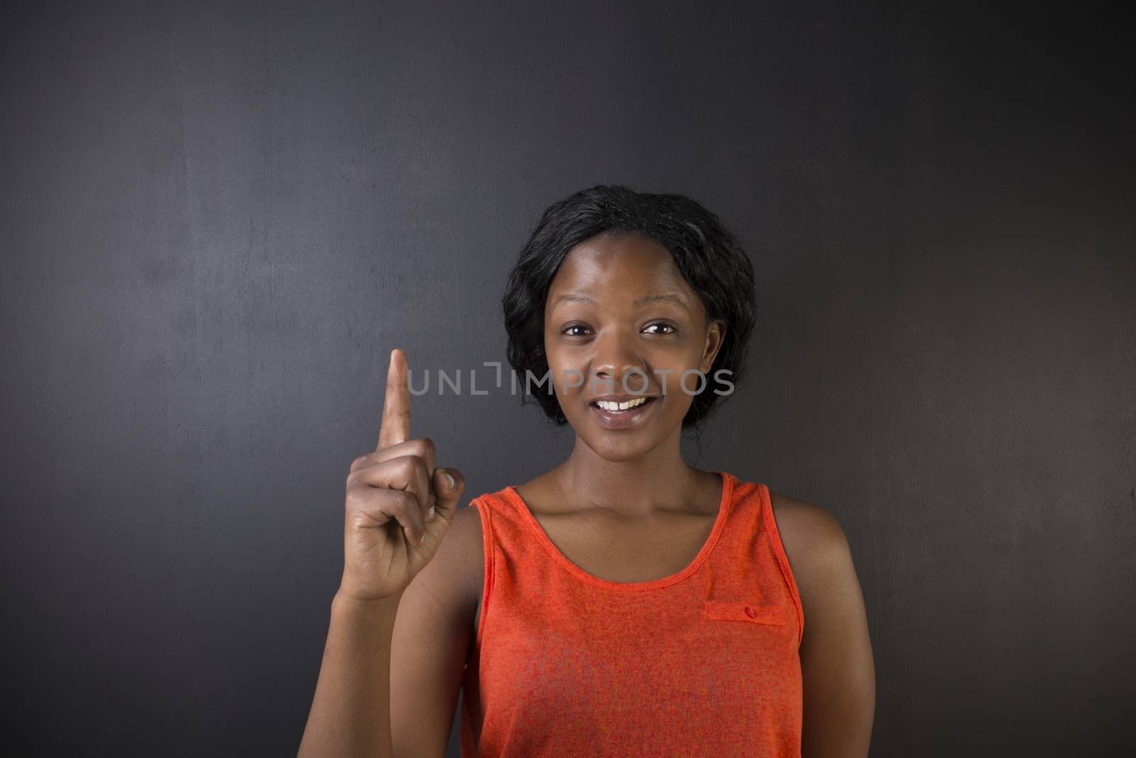 South African or African American woman teacher or student with hand up idea on chalk black board background