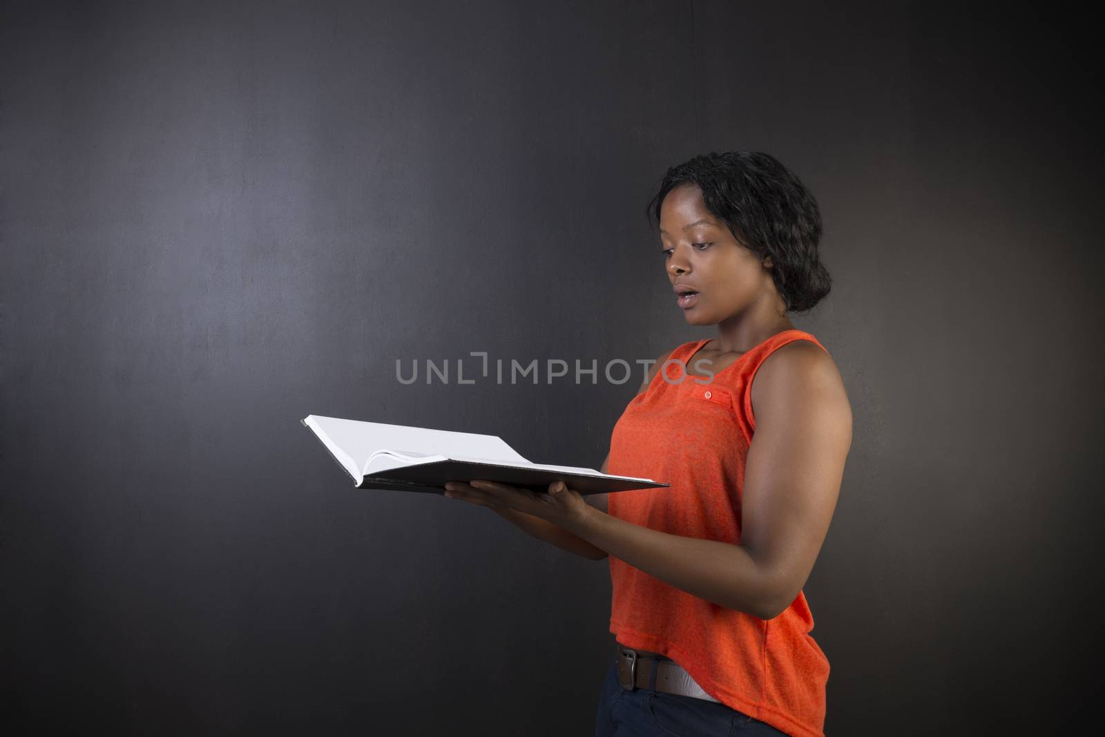 South African or African American woman teacher or student with diary notepad against a blackboard background