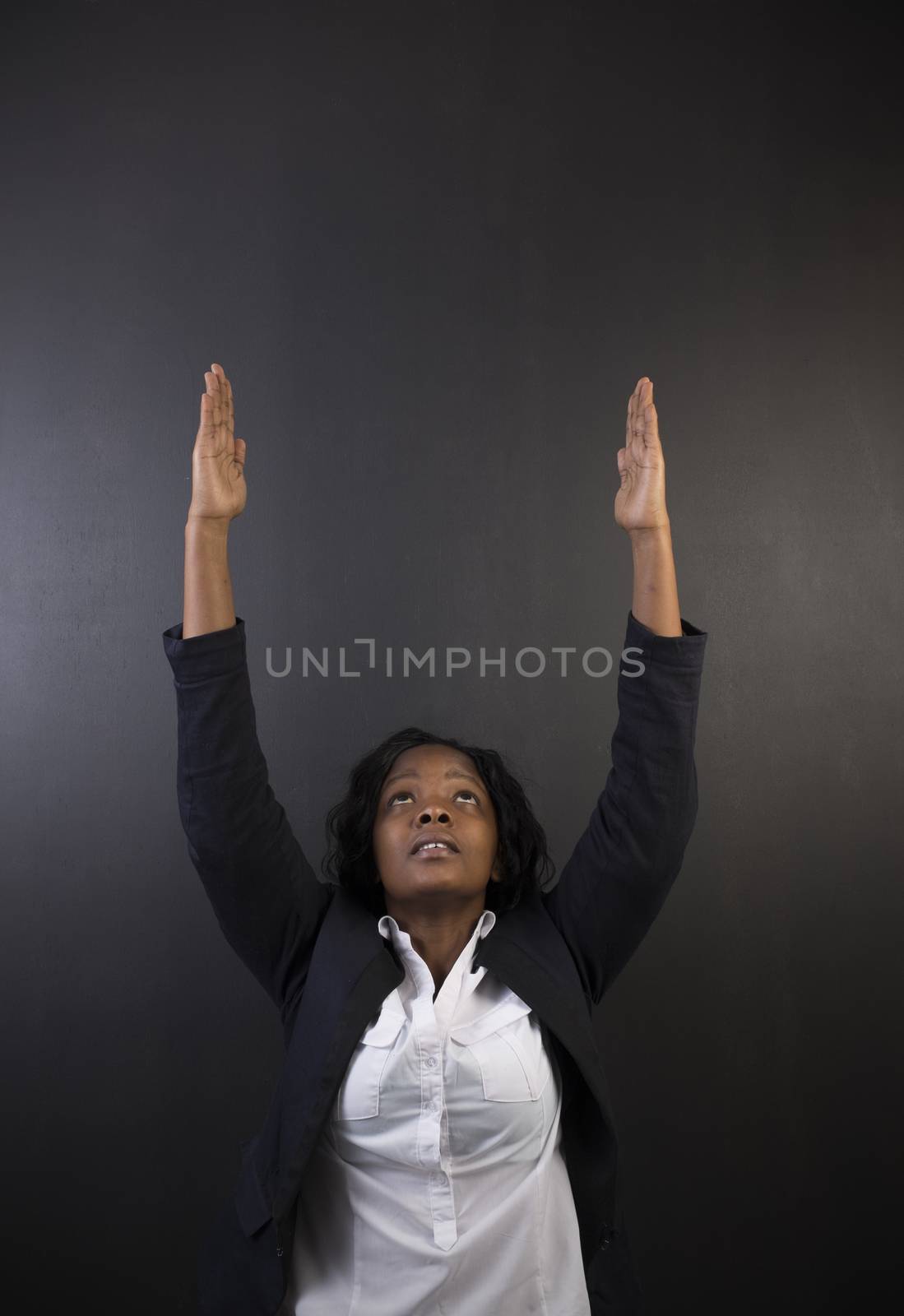 South African or African American woman teacher or student reaching for the sky on black background