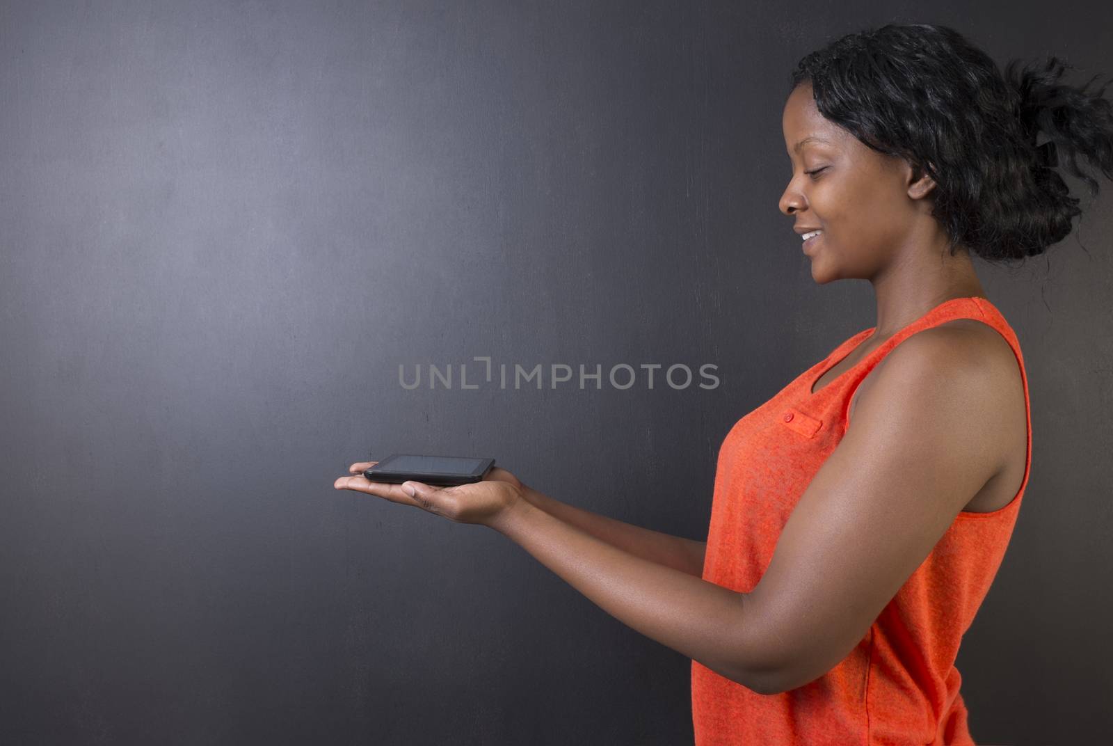 South African or African American woman teacher or student holding tablet by alistaircotton