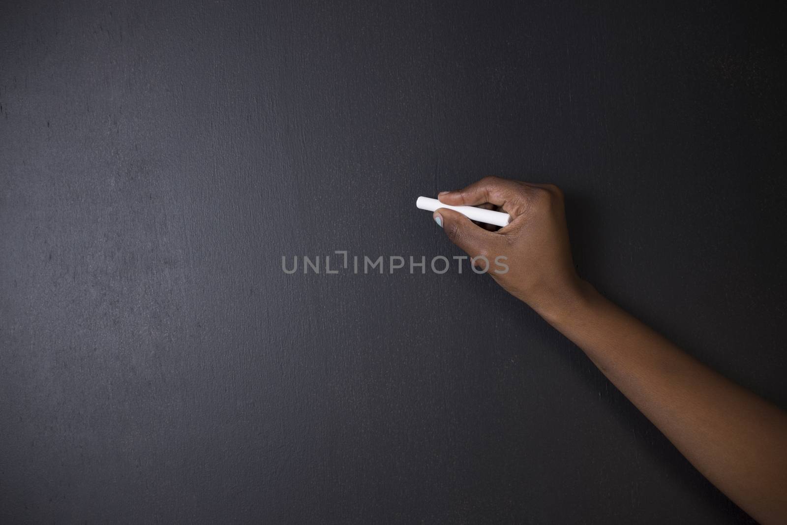 South African or African American woman teacher or student writing on chalk black board background