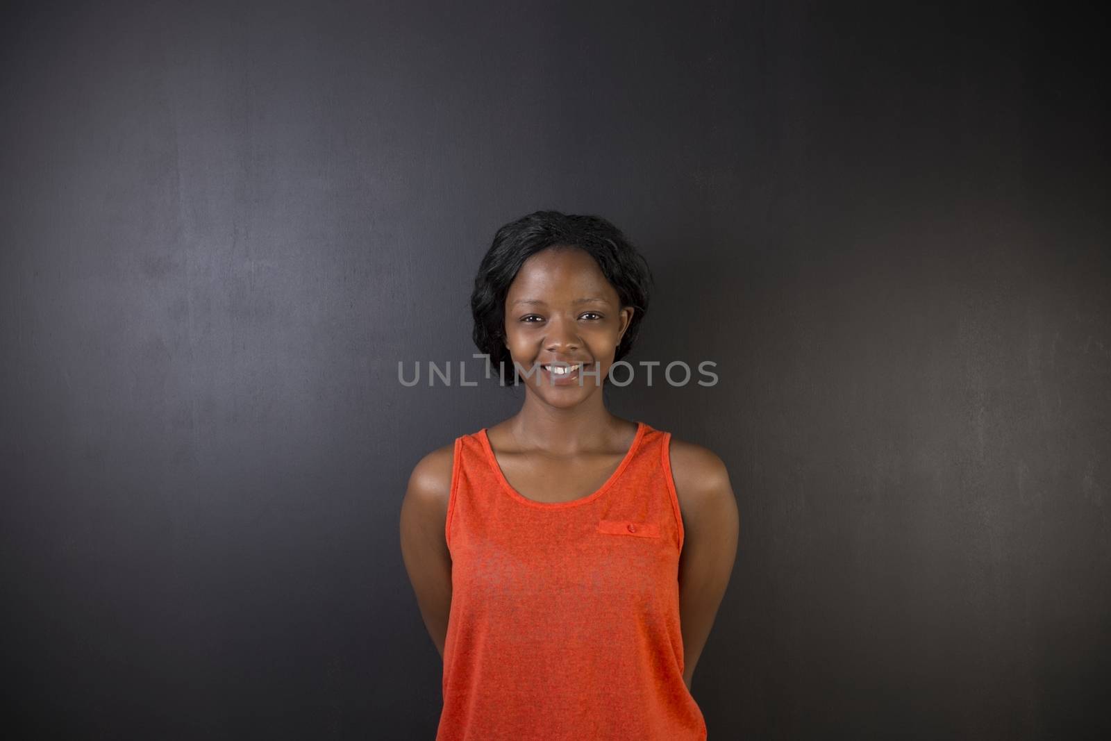 South African or African American woman teacher or student against a dark blackboard background by alistaircotton