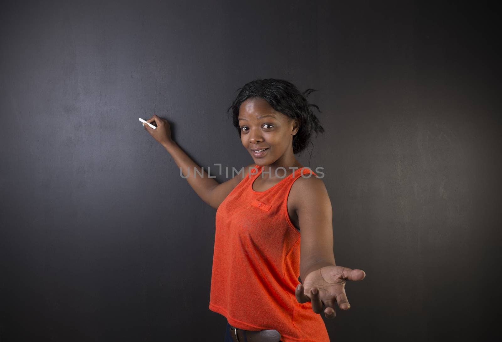 South African or African American woman teacher or student writing on blackboard by alistaircotton