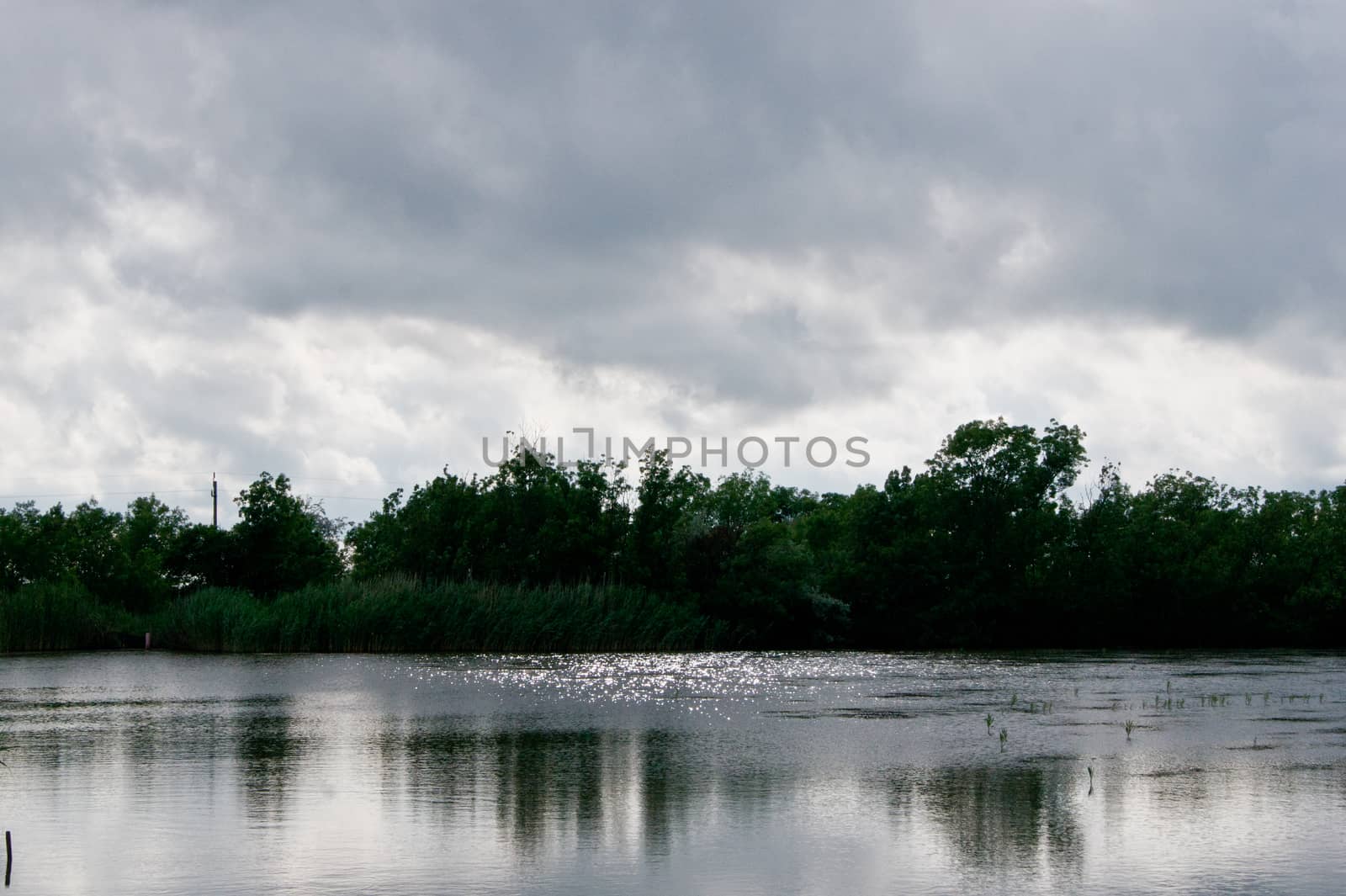 Dark clouds and water glitter on the lake .