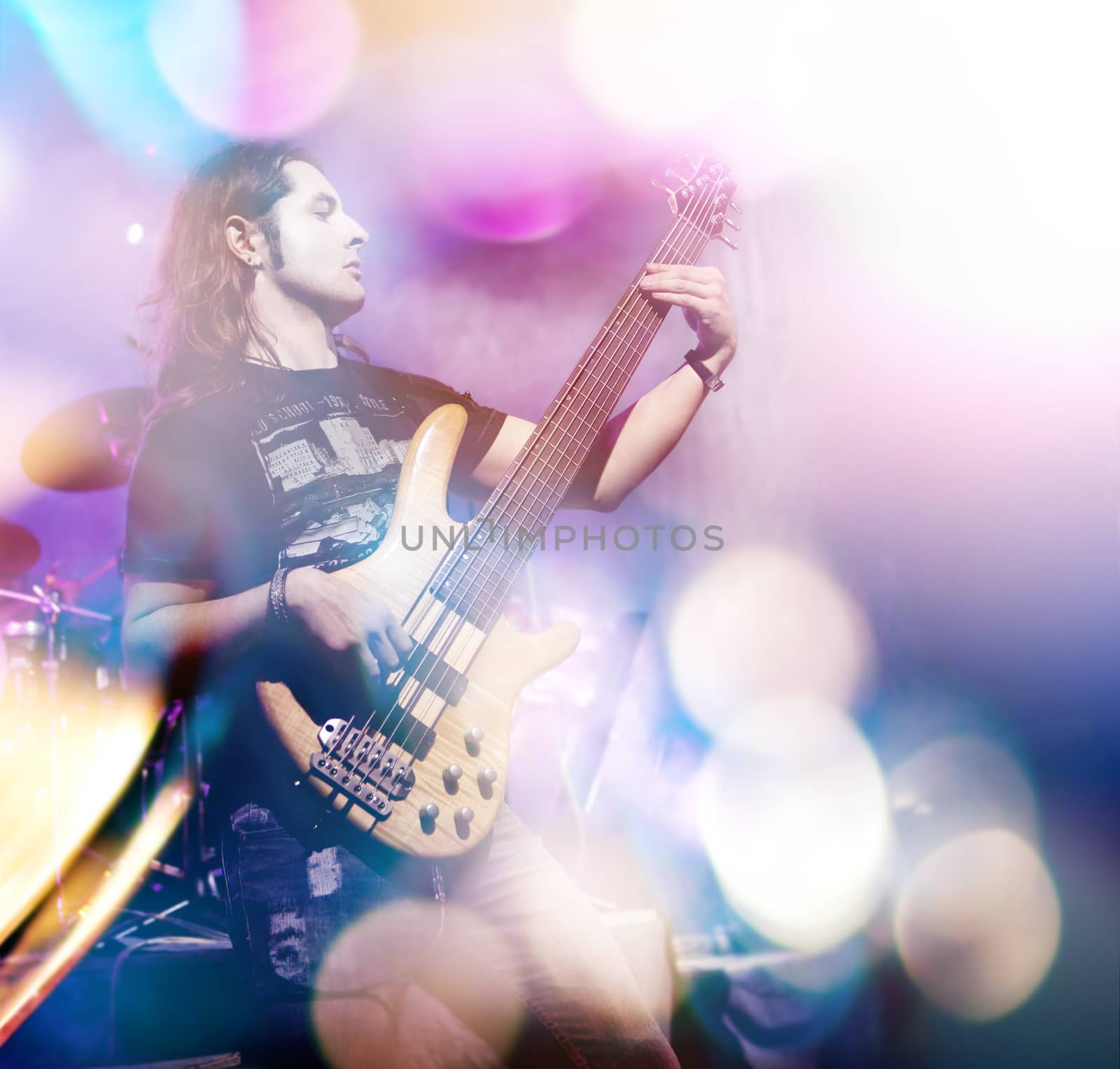 Man playing bass guitar in live concert sequence. Live music with stage lights. Double exposure