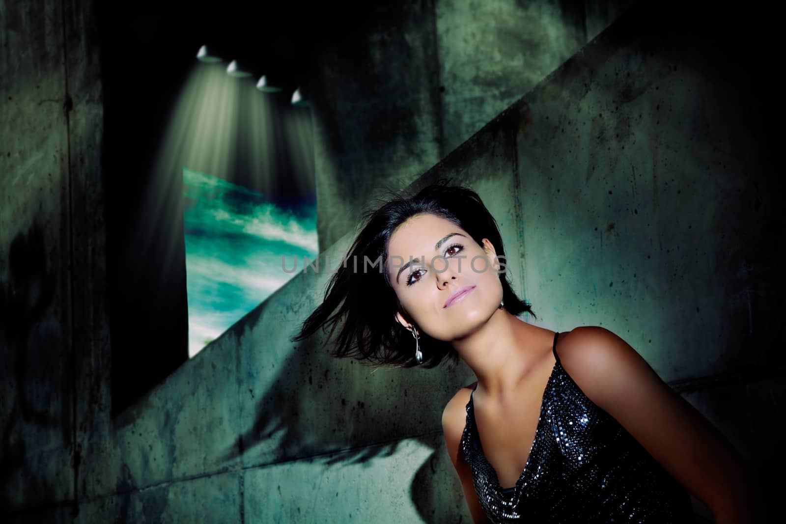 Portrait of beautiful young woman with hair in the wind and city lights background. Fashion