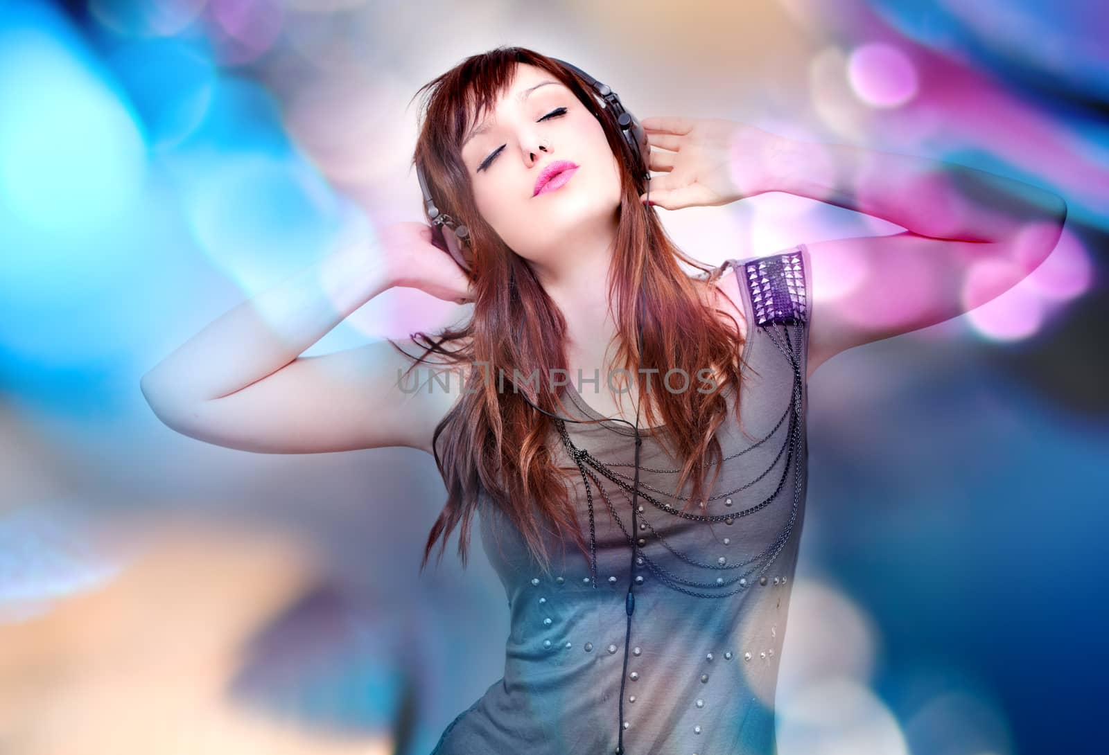 Beautiful young woman listening to music with headphones on background with stage lights. music and entertainment concept