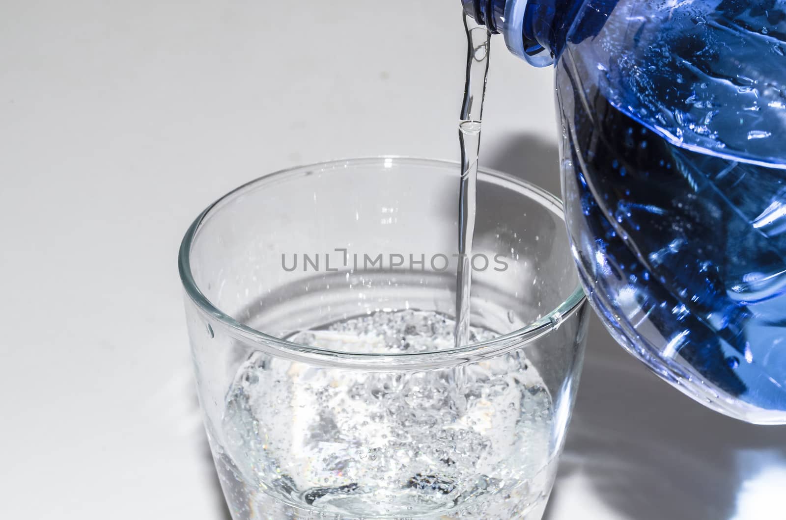 Mineral water from the bottle poured into a glass.