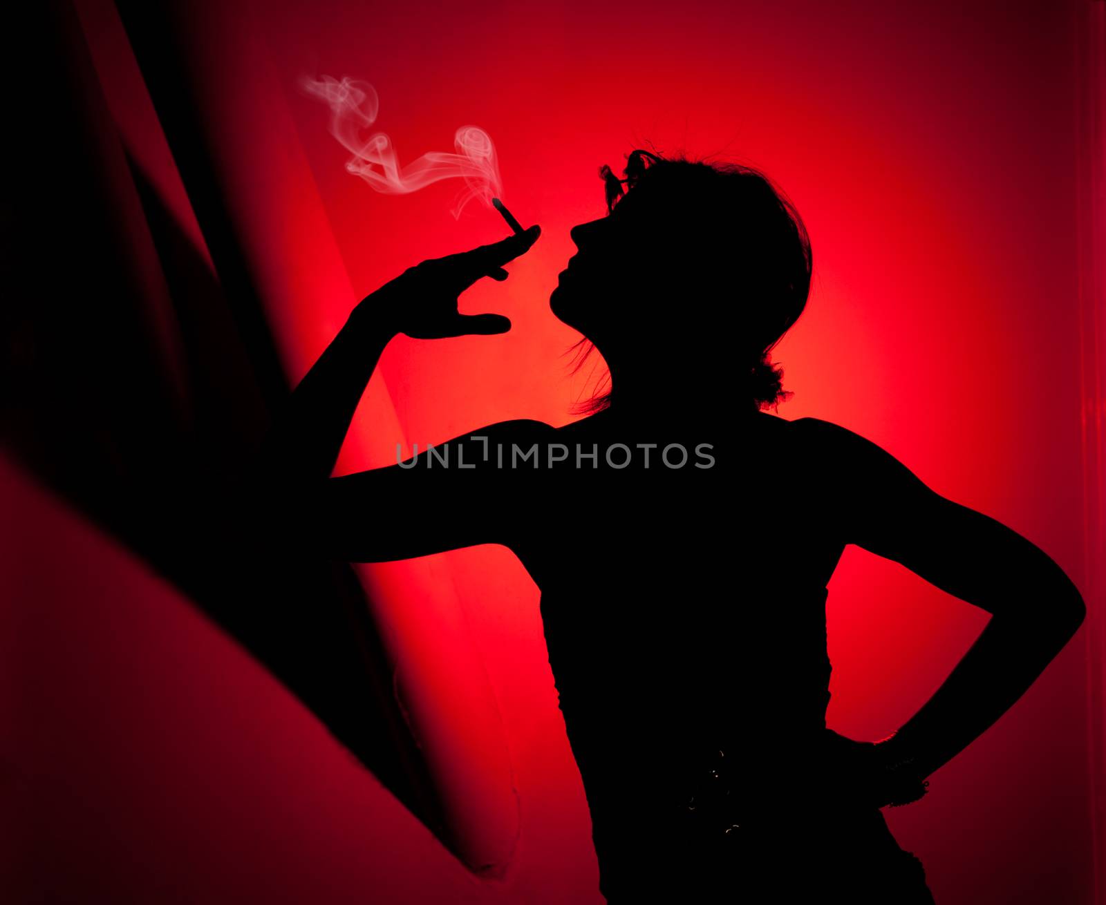 silhouette of woman smoking. Profile of woman pulling smoke on red background by Ainat