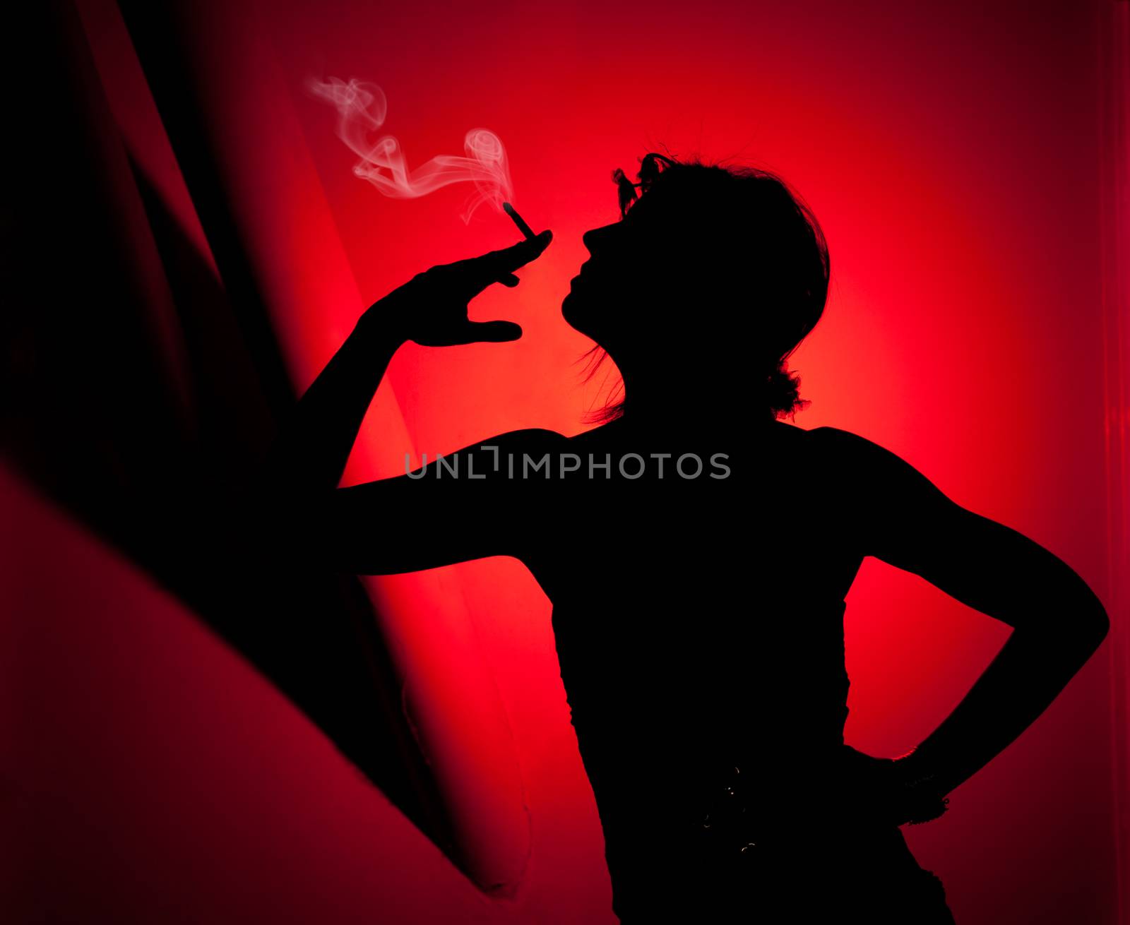 silhouette of woman smoking. Profile of woman pulling smoke on red background. Fashion