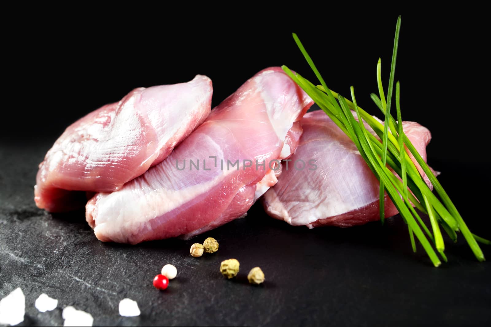 Raw meat. Fresh skinless chicken thighs on black chalkboard background by Ainat