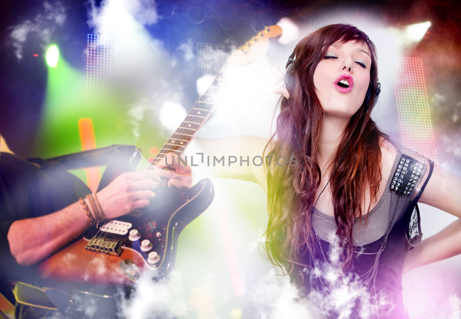 beautiful woman listening to music with headphones and singing. Live music background with guitar and bright lights on stage. Live music and party concept.