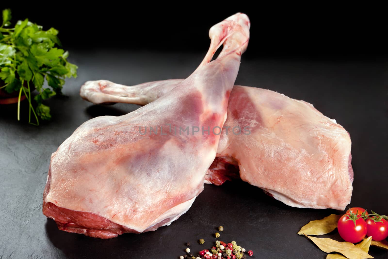 
Fresh and raw meat. Leg of lamb uncooked tomato and pepper on black background by Ainat