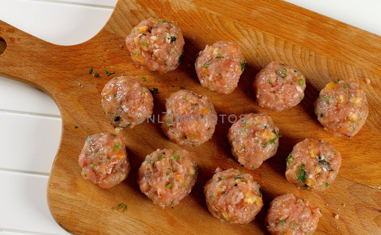 Delicious Raw Meatballs with Greens closeup on Wooden Cutting Board. Top View