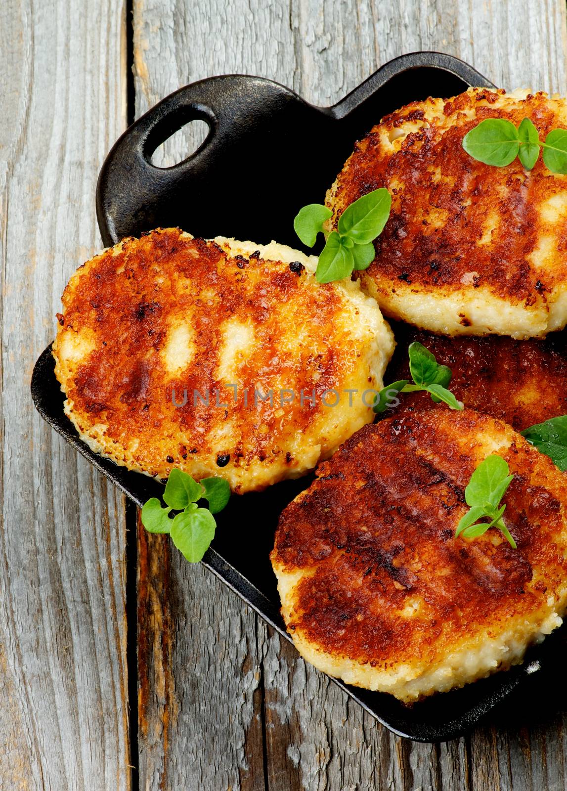 Delicious Homemade Meat Cutlets in Black Saucepan with Basil closeup on Rustic Wooden background. Top View