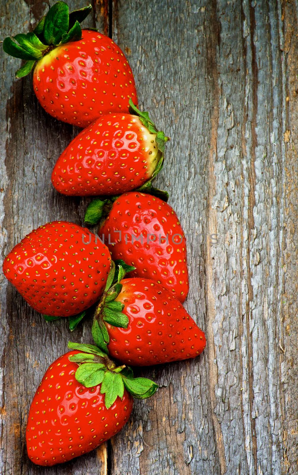 Perfect Raw Ripe Strawberries In a Row isolated on Rustic Wooden background. Top View