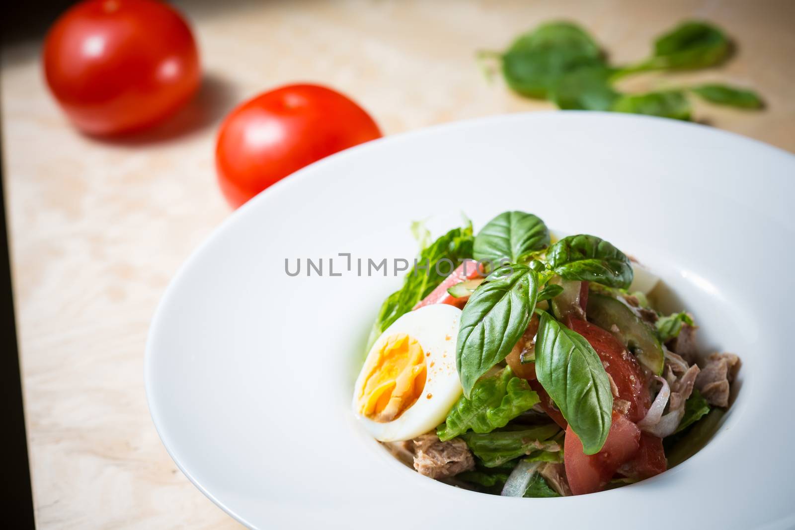 Closeup of plate of spring mix salad with strawberry, eggs and tuna