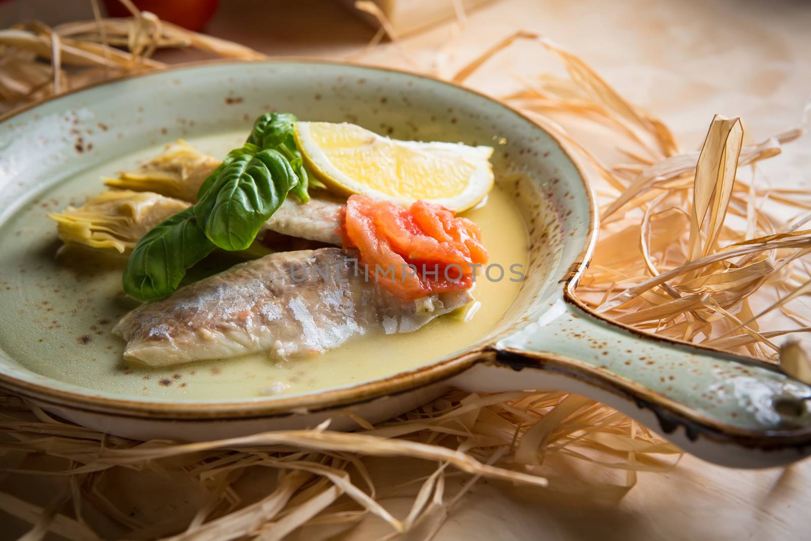 Fish fillet with artichokes and tomatoes with lemon