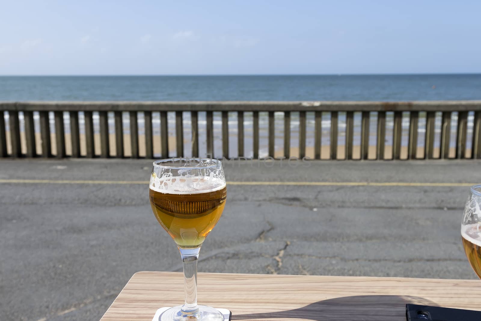 A cold beer in front of the fence and ocean