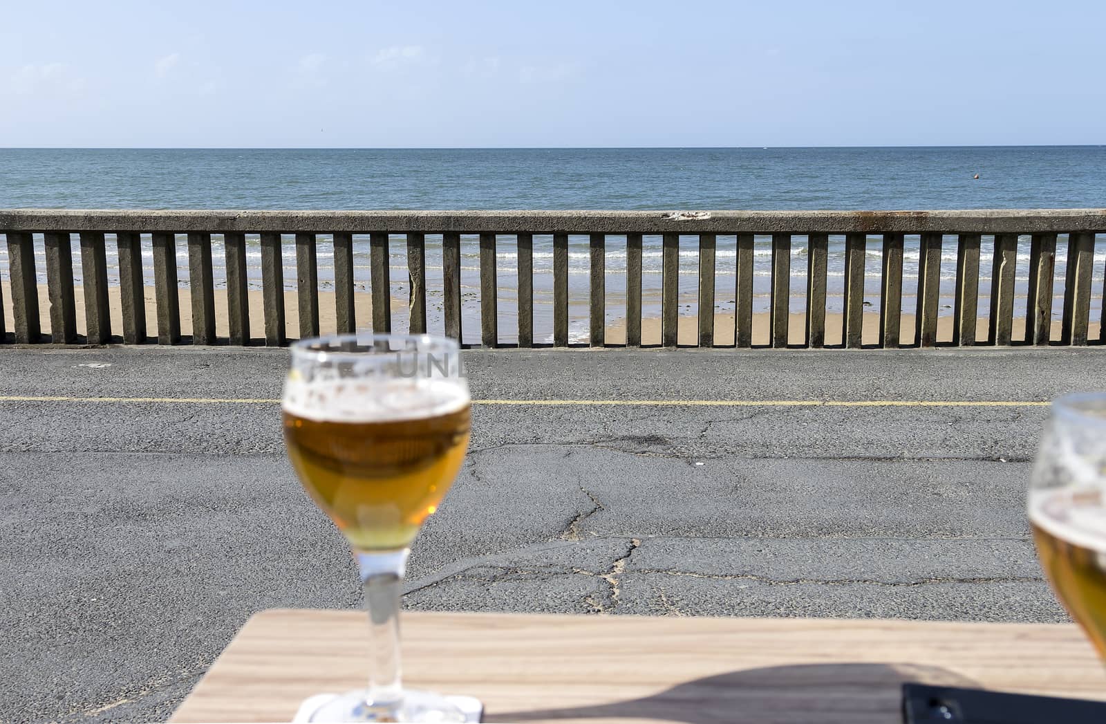 A cold beer in front of the fence and ocean