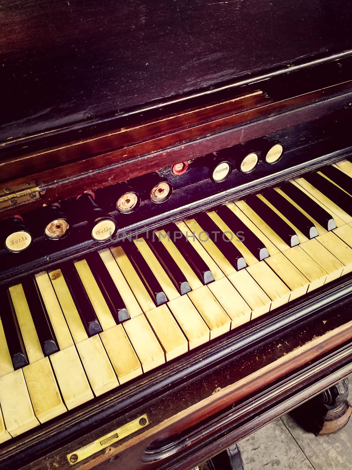 Close-up of antique reed organ keyboard and stops.