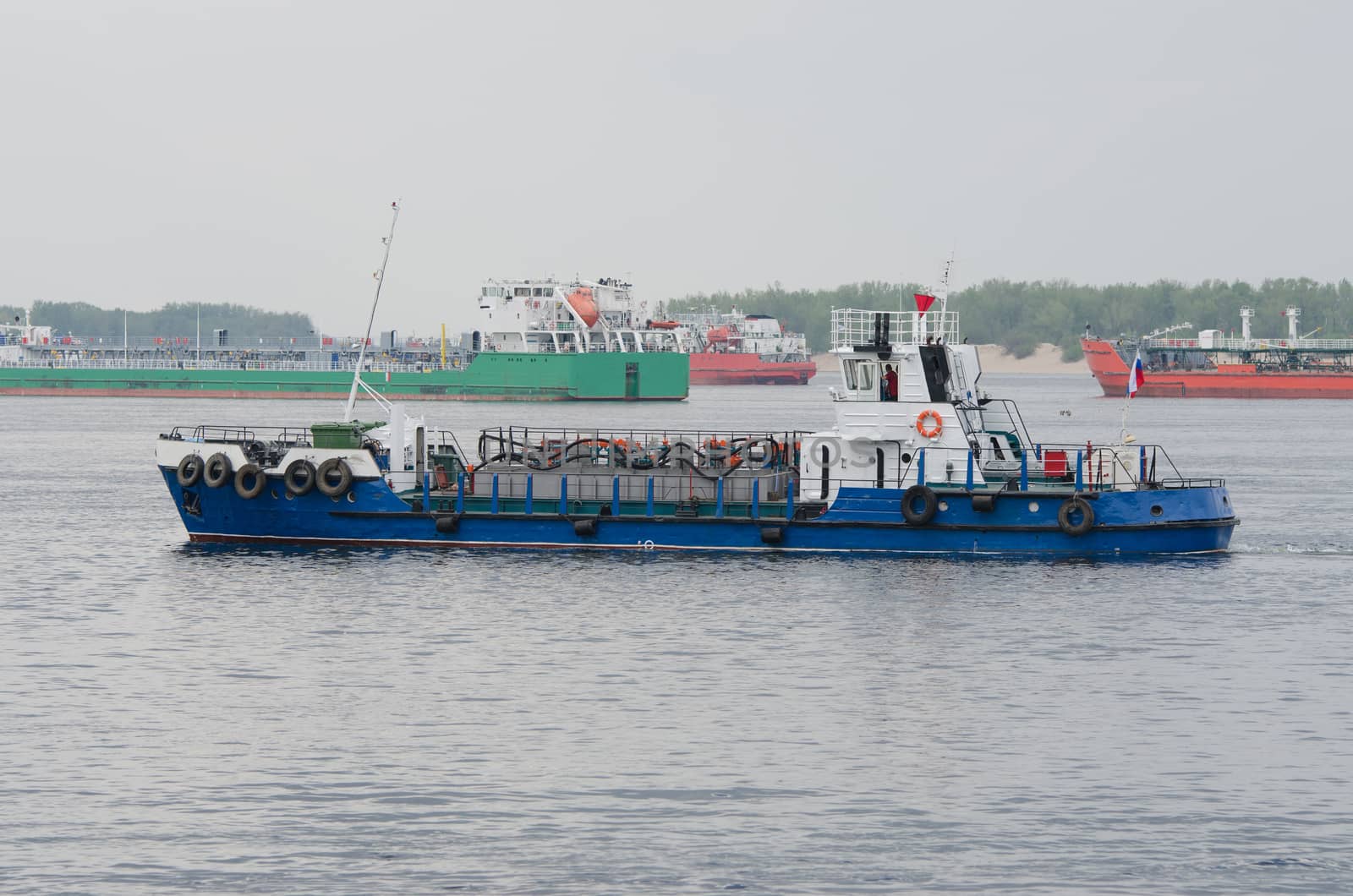 A small boat floats past standing in the roads tankers