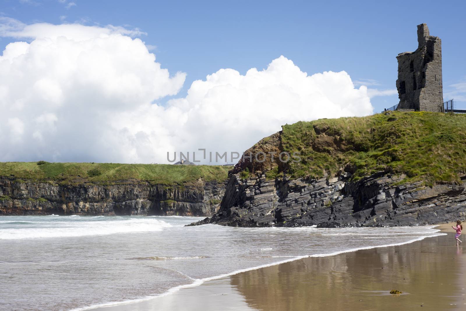 young child on the beach with cliffs and castle on ballybunion beach county kerry ireland