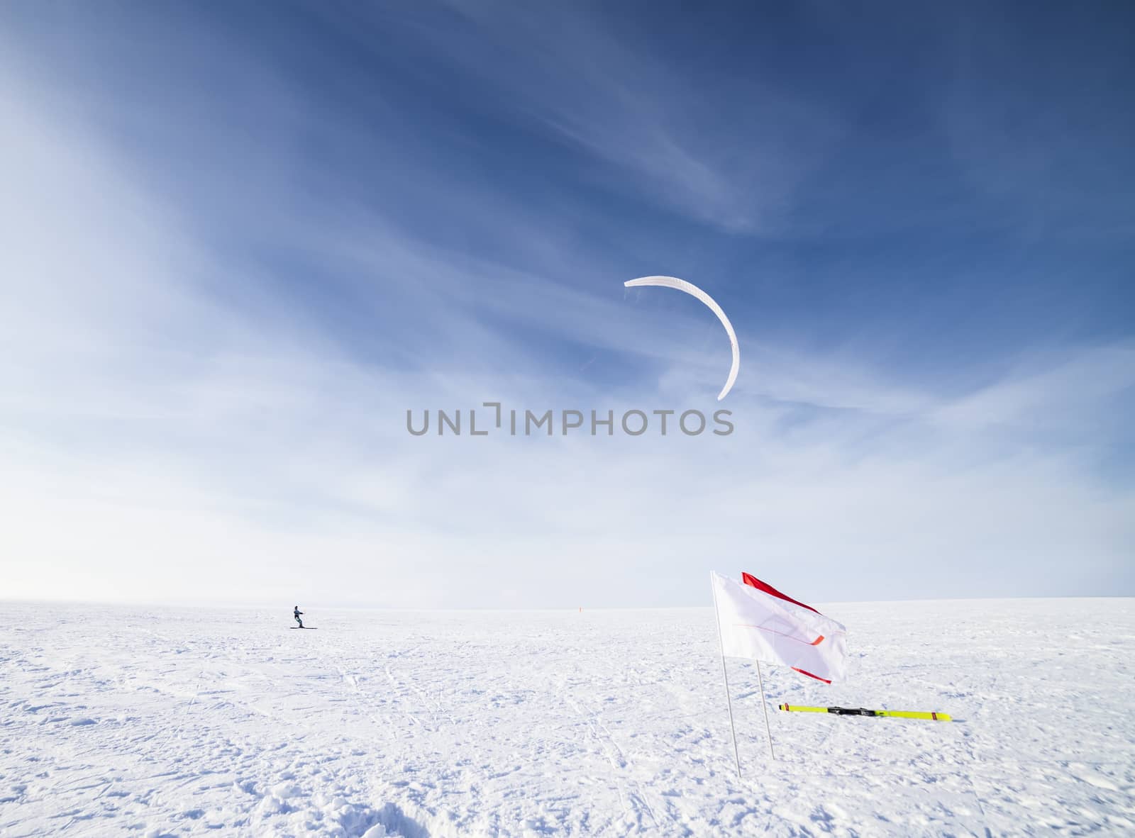 Kite boarder in snowy countryside field with cloudscape background, winter scene